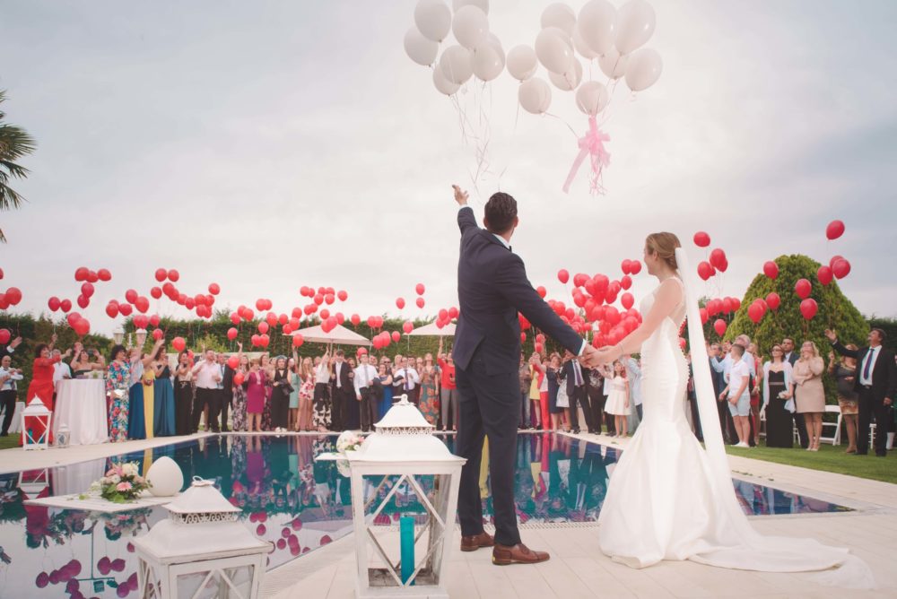 couple celebrating their wedding day with lots of guests and balloons