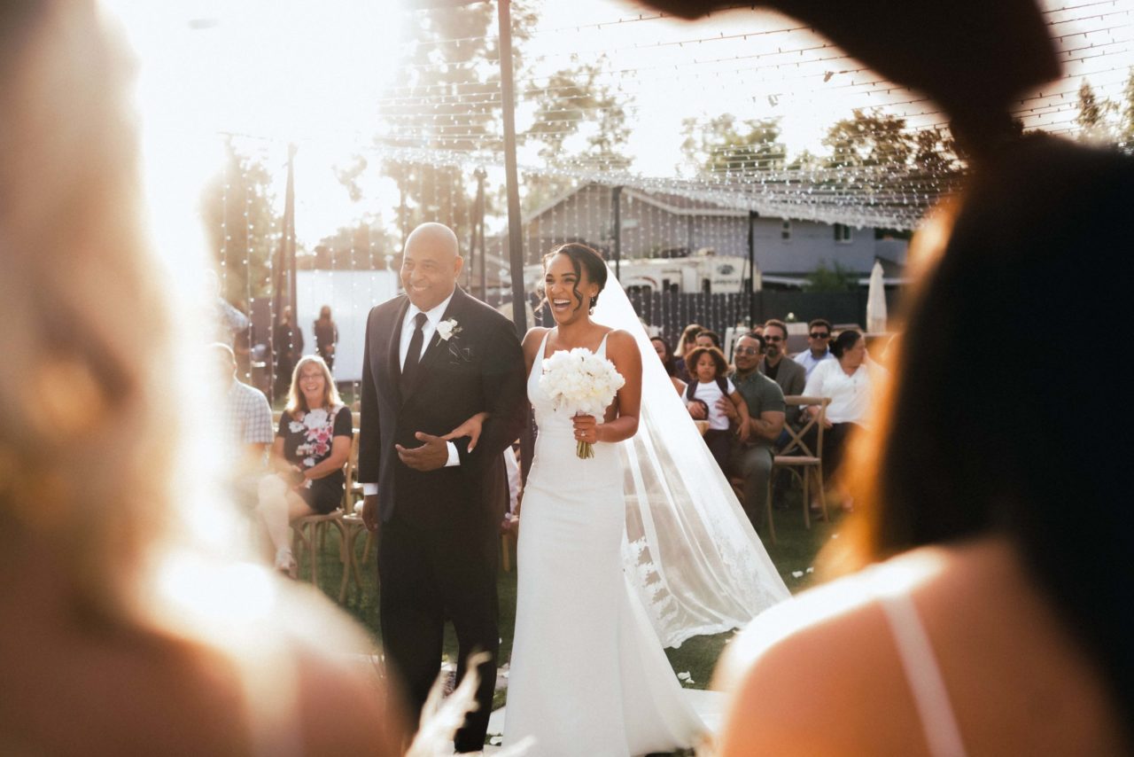 a smiling bride being walked down the aisle as planned at her wedding ceremony